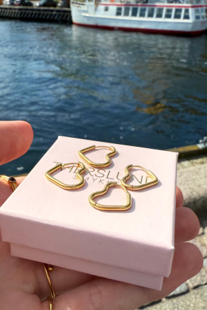 Therslund Smykker Øreringe Hjerte Creol Små Elegante hjerteformede creol fremstillet i vandfast, forgyldt rustfrit stål – et materiale, der sikrer både holdbarhed og et luksuriøst udtryk. Øreringene kan bæres enkeltvis for et minimalistisk look eller kombineres, hvis du har flere huller i ørerne, for en mere personlig og unik stil. Designet udstråler lethed og et moderne, svævende udtryk. Den varme guldnuance kombineret med det asymmetriske design giver øreringene et tidløst og feminint præg. Elina øreringene er alsidige og perfekte til enhver anledning: Festlige begivenheder som bryllupper, middage eller receptioner Et sofistikeret hverdagslook Styling med en enkel kjole, en klassisk skjorte eller andre tidløse outfits Med deres kombination af klassisk elegance og moderne detaljer er disse øreringe en stilfuld accessory, der kan løfte ethvert outfit. De er den perfekte gaveidé eller et elegant valg til både hverdag og særlige lejligheder. Alle vores smykker er nikkel- og blyfri og overholder dansk lovgivning. Vi anvender materialer som messing og rustfrit stål, ofte kombineret med glasperler eller halvædelsten, for at skabe unikke og holdbare designs.