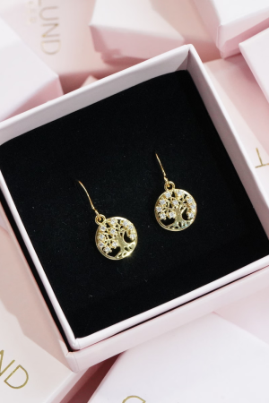 Therslund Smykker Øreringe Livets Træ Livets Træ øreringene er fremstillet i forgyldt messing og kombinerer elegance med et minimalistisk design. De er udsmykket med de smukkeste sten Øreringene er tilføjet en lethed og et moderne, svævende look. Stenenes bløde glans står i smuk kontrast til det varme guld og giver øreringene et tidløst, feminint præg. Disse øreringe er alsidige og passer perfekt til: Festlige lejligheder som bryllupper eller middage Et sofistikeret hverdagslook En enkel kjole eller en klassisk skjorte Designet forener klassisk perleelegance med et moderne, let asymmetrisk udtryk, hvilket gør dem til en stilfuld detalje, der kan løfte ethvert outfit. De er den ideelle gaveidé eller et elegant tilbehør til både hverdag og særlige anledninger. Alle vores smykker er nikkel- og blyfri og overholder dansk lovgivning. Smykkerne fremstilles i messing eller rustfrit stål og kombineres ofte med glasperler eller halvædelsten for at skabe unikke og holdbare designs.