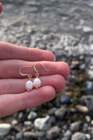 Therslund Smykker Øreringe Mille Tilføj et strejf af elegance til dit look med vores smukke Mille øreringe. Smukke og enkle ørestikker med ferskvandsperler. Øreringene tilfører en kontrast til det varme guld og giver øreringene et tidløst, feminint præg. Disse øreringe er alsidige og passer perfekt til: Festlige lejligheder som bryllupper eller middage Et sofistikeret hverdagslook En enkel kjole eller en klassisk skjorte Designet forener klassisk og let asymmetrisk udtryk, hvilket gør dem til en stilfuld detalje, der kan løfte ethvert outfit. De er den ideelle gaveidé eller et elegant tilbehør til både hverdag og særlige anledninger. Alle vores smykker er nikkel- og blyfri og overholder dansk lovgivning. Smykkerne fremstilles i messing eller rustfrit stål og kombineres ofte med glasperler eller halvædelsten for at skabe unikke og holdbare designs.