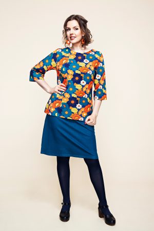 Cissi Och Selma Bluse Vendela Vendela-blusen er en elegant A-formet top fremstillet i blød, økologisk bomuldsjersey med 3/4-ærmer. Designet er figursyet med en smallere overdel og en mere vidde forneden, hvilket skaber en flatterende silhuet. De diskrete slidser i siderne bidrager til en behagelig og fleksibel pasform. Blusen er dekoreret med et iøjnefaldende blomstermønster med store blomster i varme orange og gule nuancer på en dyb blå baggrund. Farvepaletten er inspireret af 70'ernes retrostil og giver et unikt og stilfuldt udtryk. Cissi och Selma Bluse Vendela har en lige pasform. Hvis du foretrækker en mere tætsiddende model, anbefales det at vælge en størrelse mindre. Stoffet er strækbart og tilpasser sig kroppen for optimal komfort.