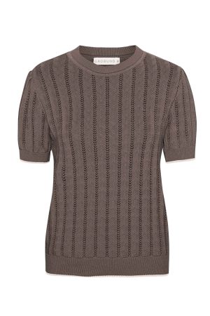 Grobund T-shirts Almine Nougat Almine strik tee fra GROBUND er en elegant og komfortabel t-shirt fremstillet i en eksklusiv strikkvalitet af økologisk bomuld. Det fine pointelle-strik skaber et delikat hulmønster og tilfører blusen en unik struktur og et raffineret udtryk. Den smukke soft rose farve giver strikteen et frisk og sofistikeret look, der kan løfte ethvert outfit. Strikteen har en klassisk pasform, og de korte ærmer er designet med en diskret puff-effekt, der tilføjer et feminint touch til det samlede udtryk. Som altid er Almine tee 100% GOTS-certificeret, så du kan bære den med god samvittighed. Se udvalget fra Grobund her