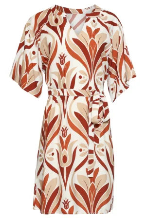 Smashed Lemon Kjole 26189 Denne luftige tunikakjole fra Smashed Lemon udstråler ren glæde. Kjolen er dekoreret med et smukt, stort retroprint med blomstermotiver i livlig orange og blid beige. Det er det perfekte stykke tøj til kvinder, der holder af et legende, men elegant look. Kjolen har en diskret V-udskæring og markante, vide ærmer, der giver en flagrende effekt. Det løse snit gør kjolen vidunderligt behagelig, mens det matchende bælte i taljen giver mulighed for at fremhæve figuren. Tilfør et strejf af farve til din dag med denne unikke kreation fra Smashed Lemon. Nøglefunktioner: Boheme-ærmer: Vide ærmer, der skaber et luftigt og legende udtryk. Alsidig stil: Kan bæres løst eller spændes ind i taljen med det medfølgende bælte. Iøjnefaldende retrolook: Et unikt print, der forener klassiske blomstermotiver med moderne farvenuancer.