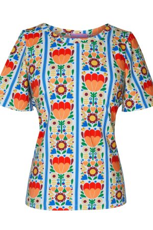 Margot T-Shirts Miss Flowerwall Blusen har et farverigt og tydeligt retroinspireret design med stærke referencer til skandinavisk folkekunst og 60’er/70’er-mode. En lys creme/hvid bund med klare orange, røde, blå, grønne og gule detaljer giver et meget livligt udtryk. Symmetrisk blomster- og hjertemotiv arrangeret i lodrette paneler. Det minder om klassiske folk art- eller nordiske tapetmønstre. Enkel og let figursyet pasform, som gør det mønstrede design til fokuspunktet. Korte, lidt løse ærmer giver et afslappet og sommerligt look.  Rund hals gør blusen nem at style både casual og mere feminint. Glad, kunstnerisk og vintagepræget — næsten som en moderne fortolkning af retro-svensk eller boheme-inspireret mode.