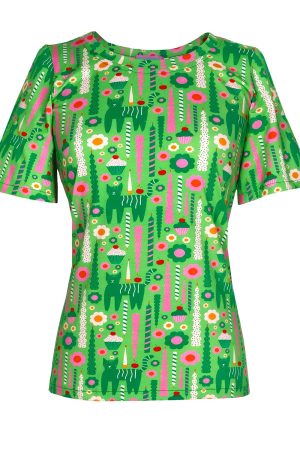 Margot T-Shirts Miss Celebration Blusen har et meget farverigt og legende design med en klar grøn bundfarve. Mønstret er fyldt med små illustrationer i retrostil, blandt andet: Grønne katte med striber Blomster i pink, hvid og orange Cupcakes og kirsebær Lange dekorative lys eller søjler i forskellige mønstre Rund halsudskæring Korte ærmer En lige og afslappet pasform Stilen virker kreativ, retro og lidt skandinavisk i udtrykket — meget iøjnefaldende og glad i farverne. Den kunne passe godt til ensfarvede bukser eller nederdel, så mønstret får fokus