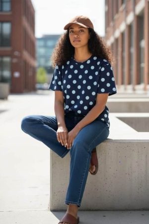 Ofelia T-shirts Navy Blue Blusen har et enkelt, moderne og afslappet udtryk med et klassisk mønster. Den er udført i en mørk navy blå farve med store hvide prikker, som giver et tidløst og friskt look. Blusen har en rund halsudskæring, hvilket understreger det enkle design. korte, let løse ærmer, som giver god bevægelsesfrihed og et afslappet fald. Pasformen er rummelig, så den falder flot uden at sidde tæt til kroppen. Stoffet er 100 % bomuld der giver blusen et livligt udtryk, samtidig med at farvekombinationen gør den nem at style. Blusen passer godt sammen med jeans, chinos eller en enkel nederdel. Den kan bruges både til en afslappet hverdag med sneakers eller sandaler og styles mere klassisk med en blazer eller cardigan.